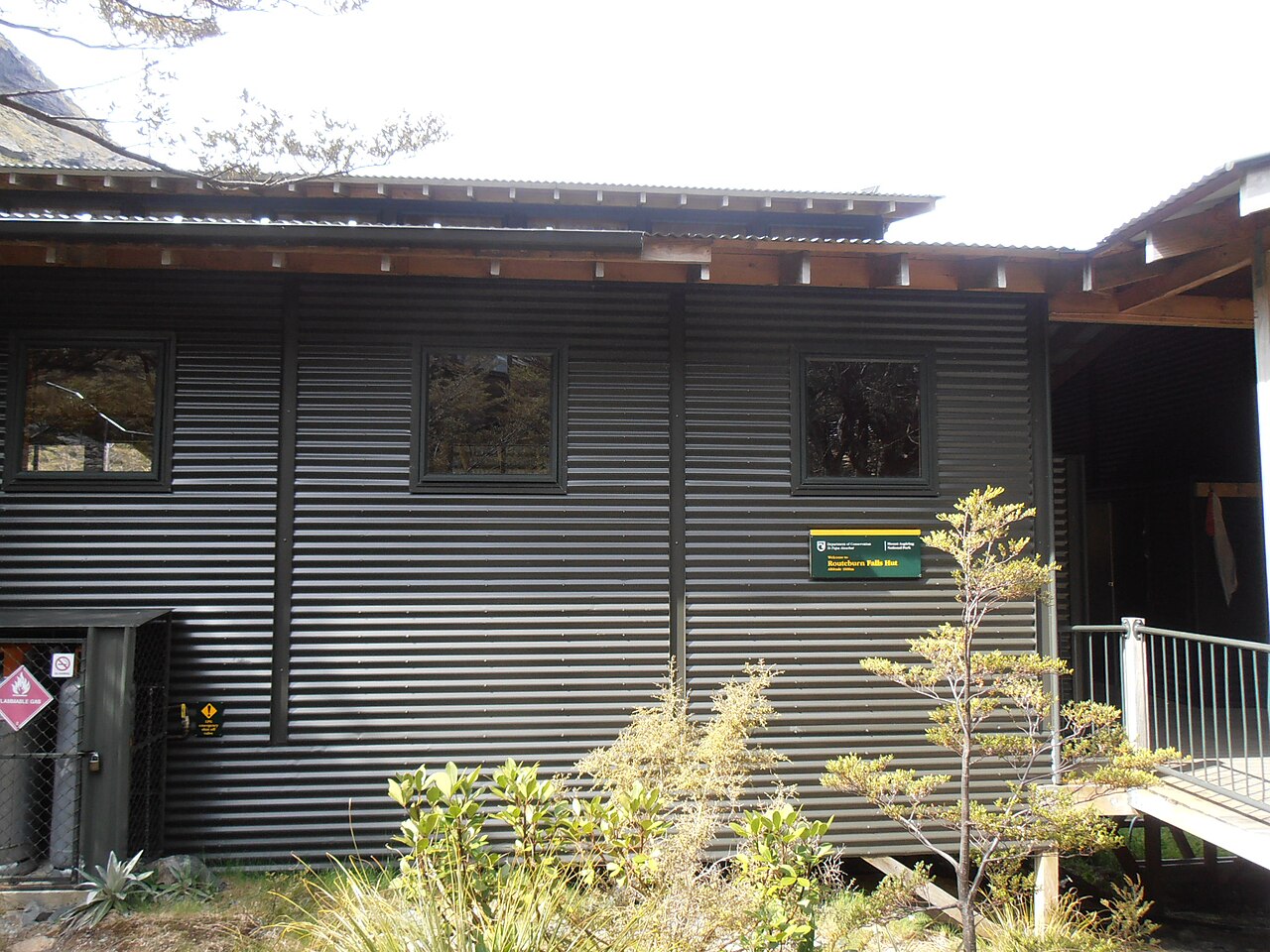 The timber entrance and deck of Routeburn Falls Hut, with steps leading up to the door.
