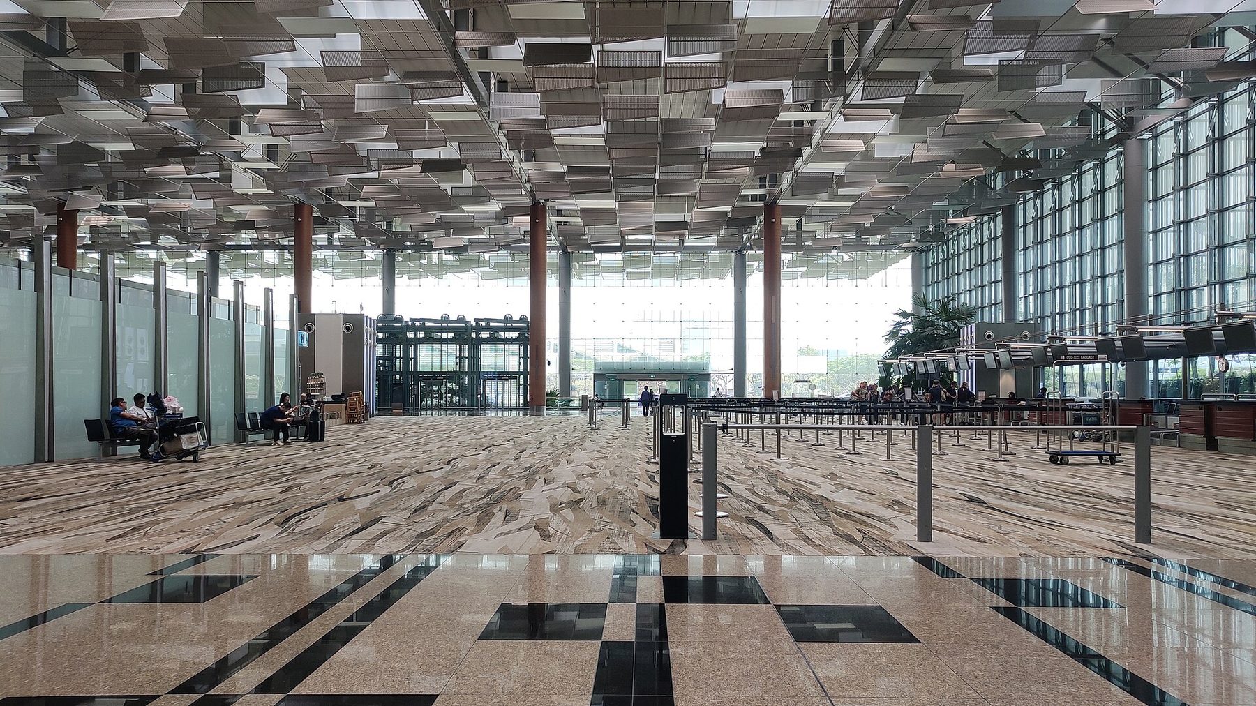 The wide skylit departure hall of Changi Airport Terminal 3, with check-in rows, hanging light panels and travelers crossing the polished floor