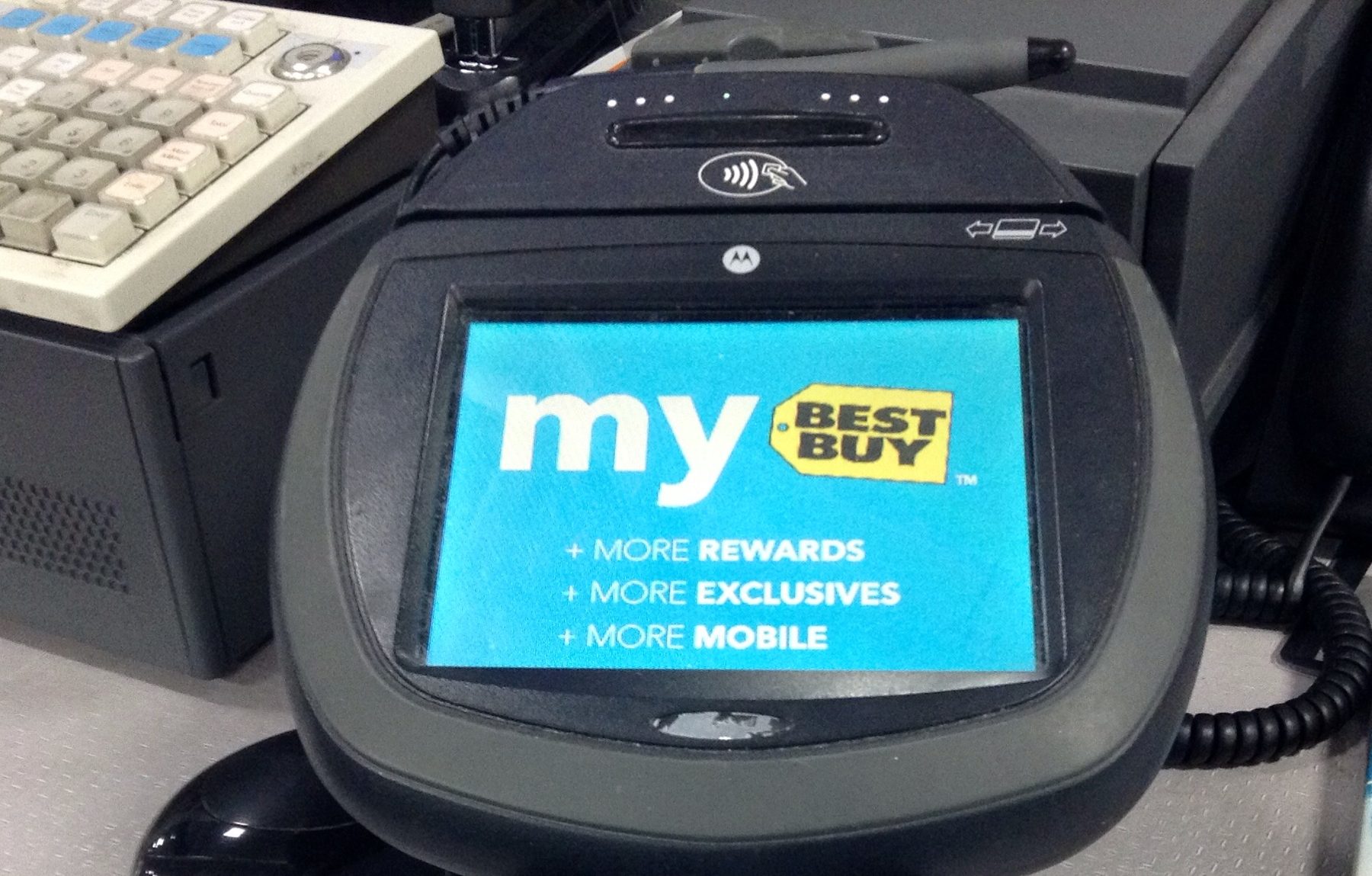 A credit card being swiped through a point-of-sale card reader at a retail checkout counter