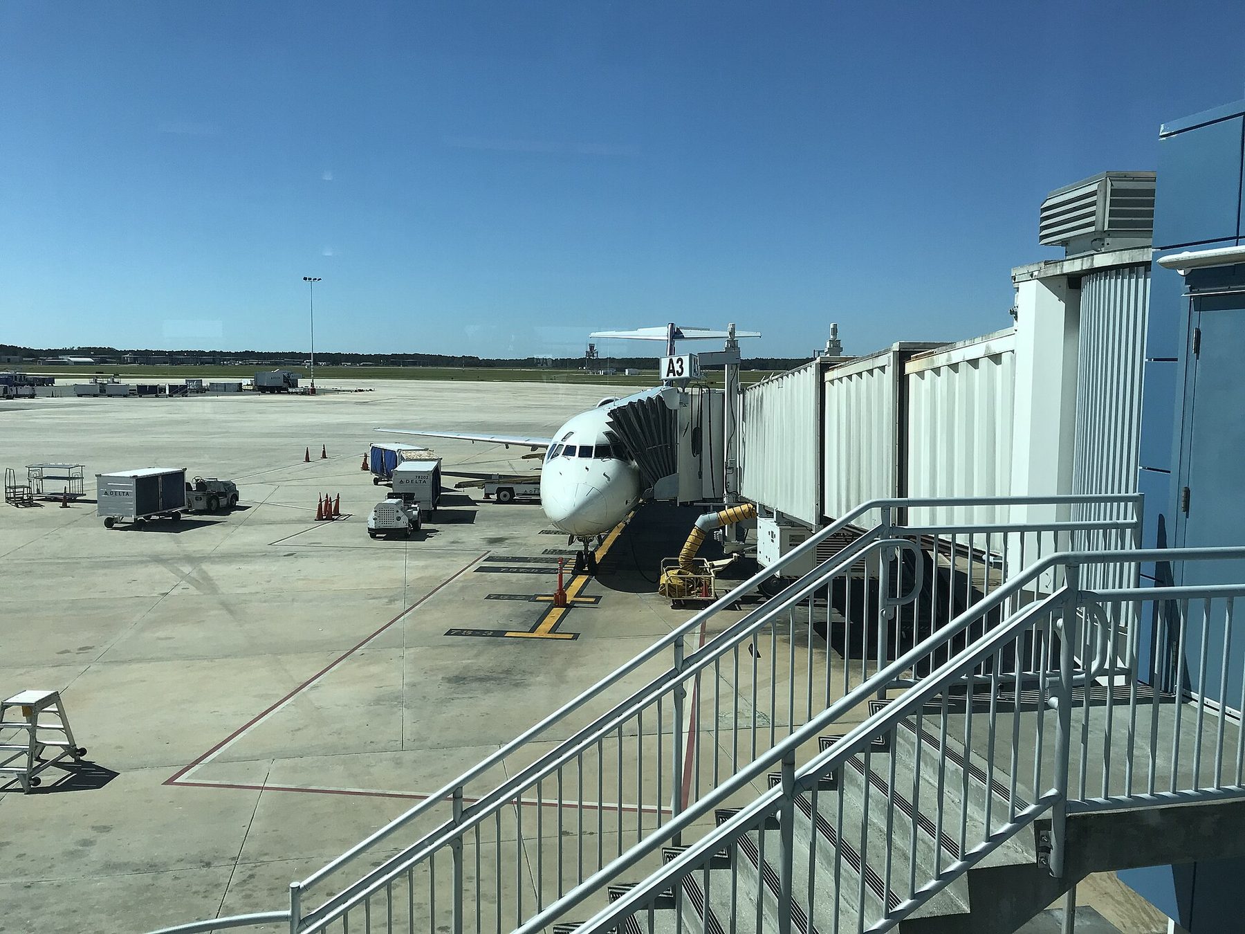 An airport gate area with a jet bridge and an aircraft visible through the windows, boarding in progress