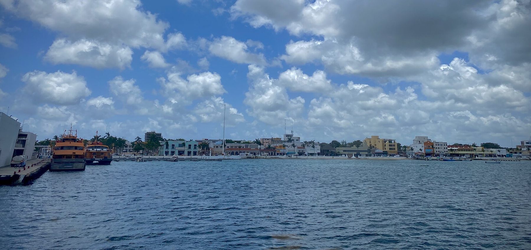 San Miguel de Cozumel seen low across open blue water from the deck of a passenger ferry