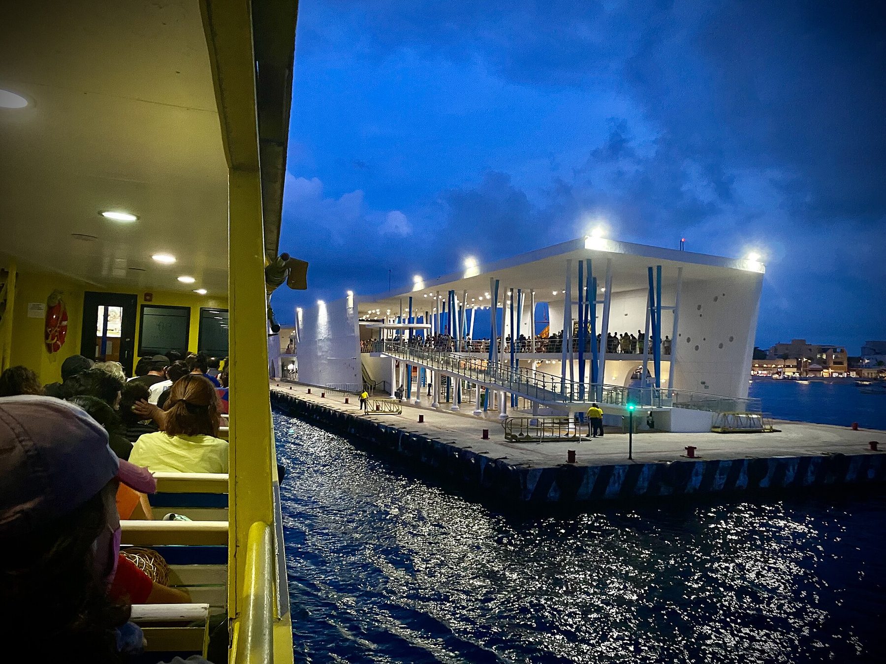 A white passenger ferry alongside the concrete dock at San Miguel de Cozumel, with the waterfront town behind it