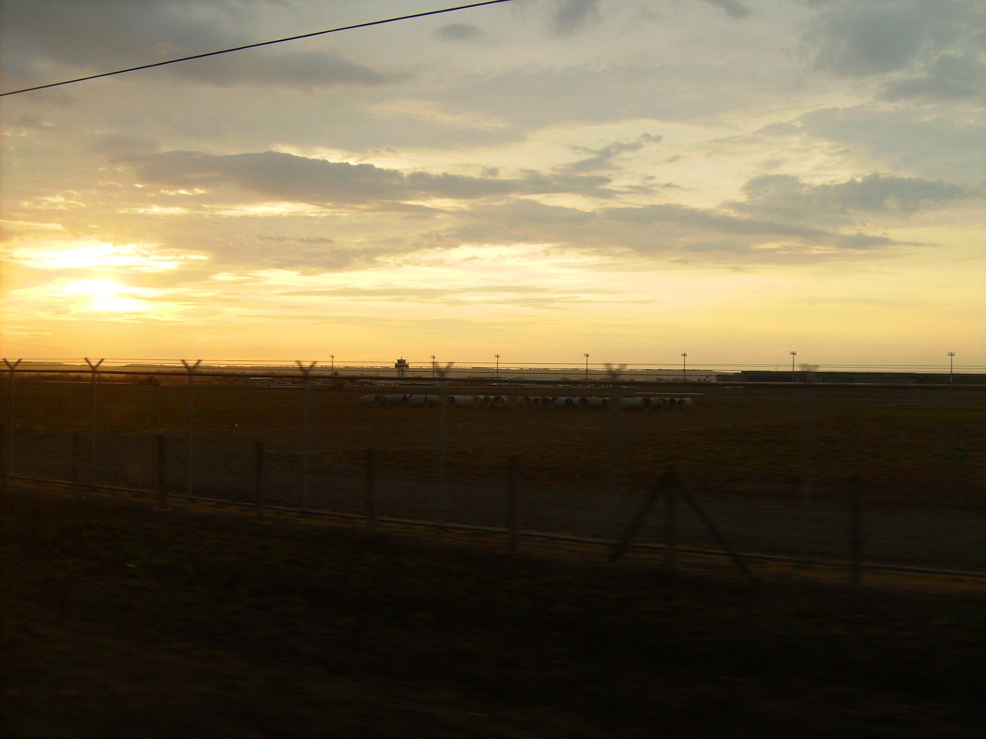 The runway, control tower and perimeter fence of Daniel Oduber Quirós International Airport in Liberia, Costa Rica, at sunset