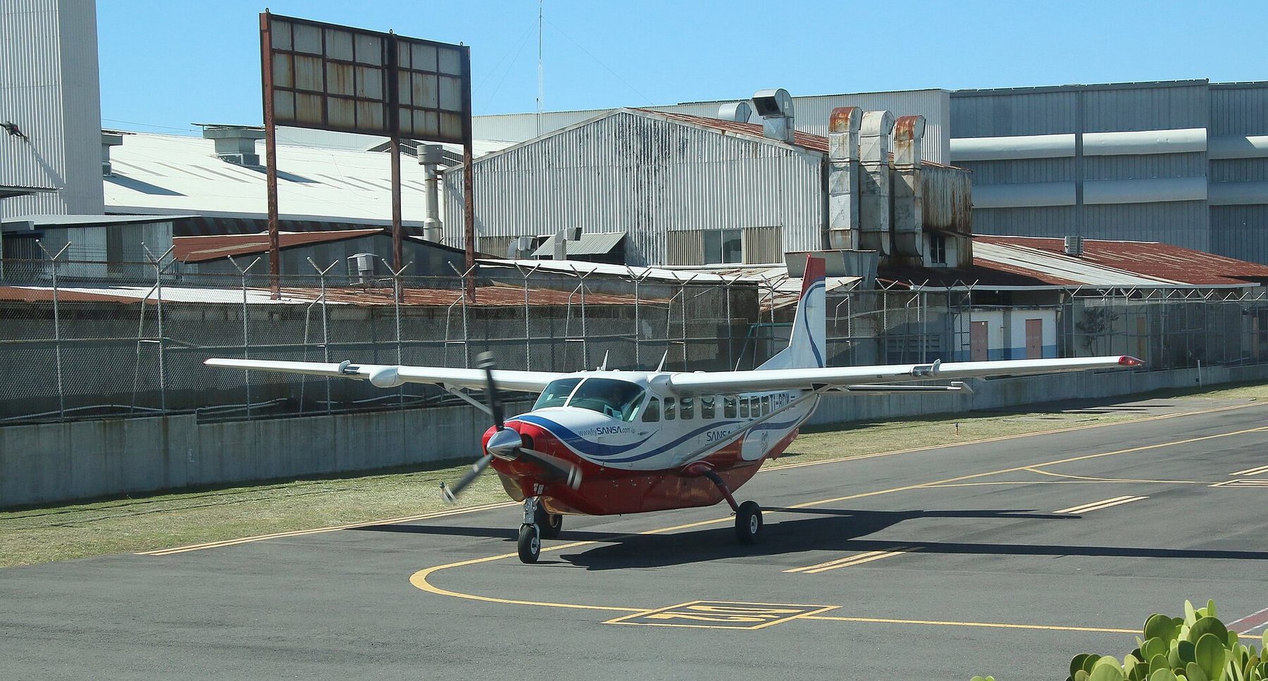 A small single-engine Cessna Grand Caravan in white and blue livery on an airport apron
