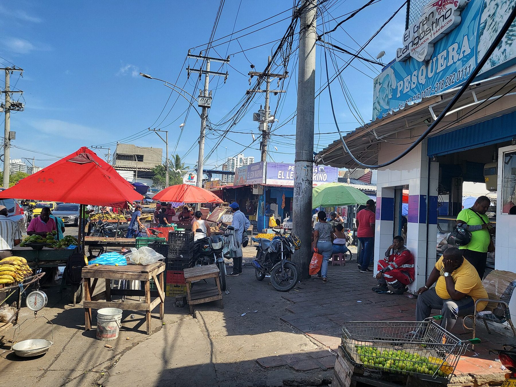 Crowded stalls and stacked produce under corrugated roofing at Mercado de Bazurto in Cartagena, with traders and shoppers in the aisles.