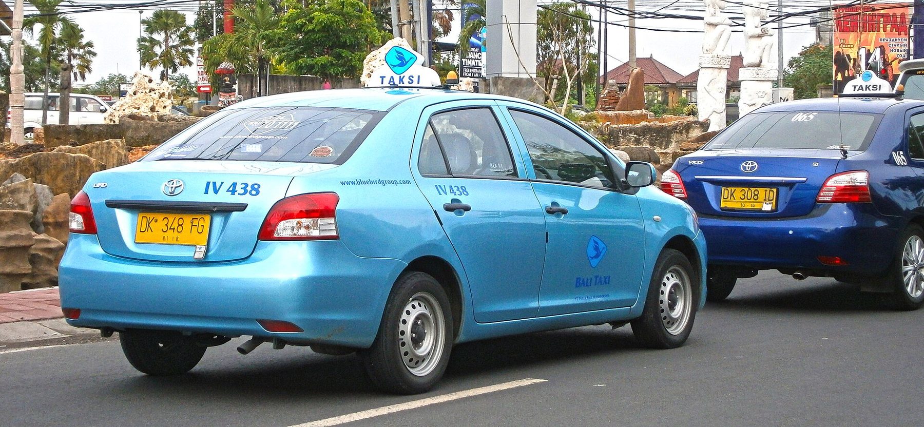 A blue Toyota Limo taxi with a Blue Bird Group roof sign on a street in Kuta, Bali