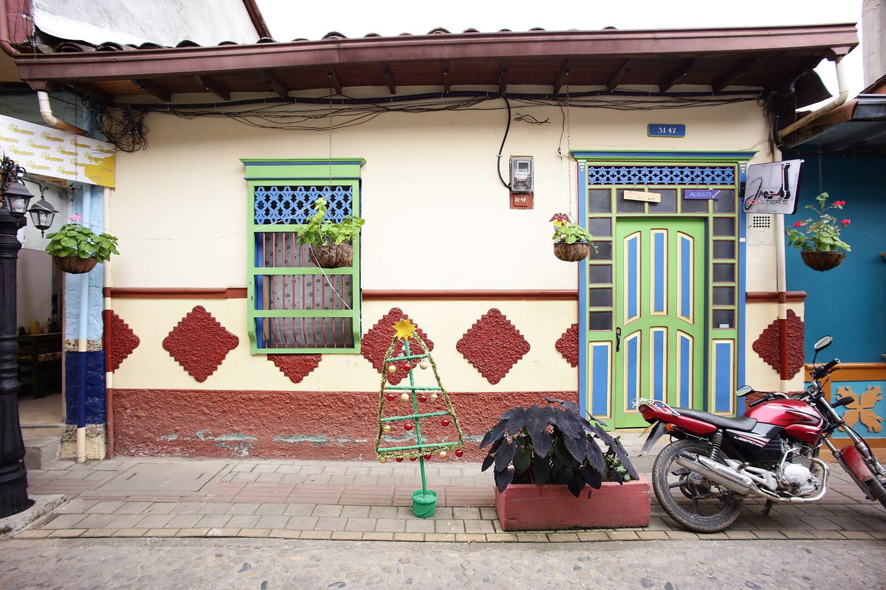 A house front in Guatapé painted in bright colours, with a raised relief panel of geometric shapes running along the base of the wall