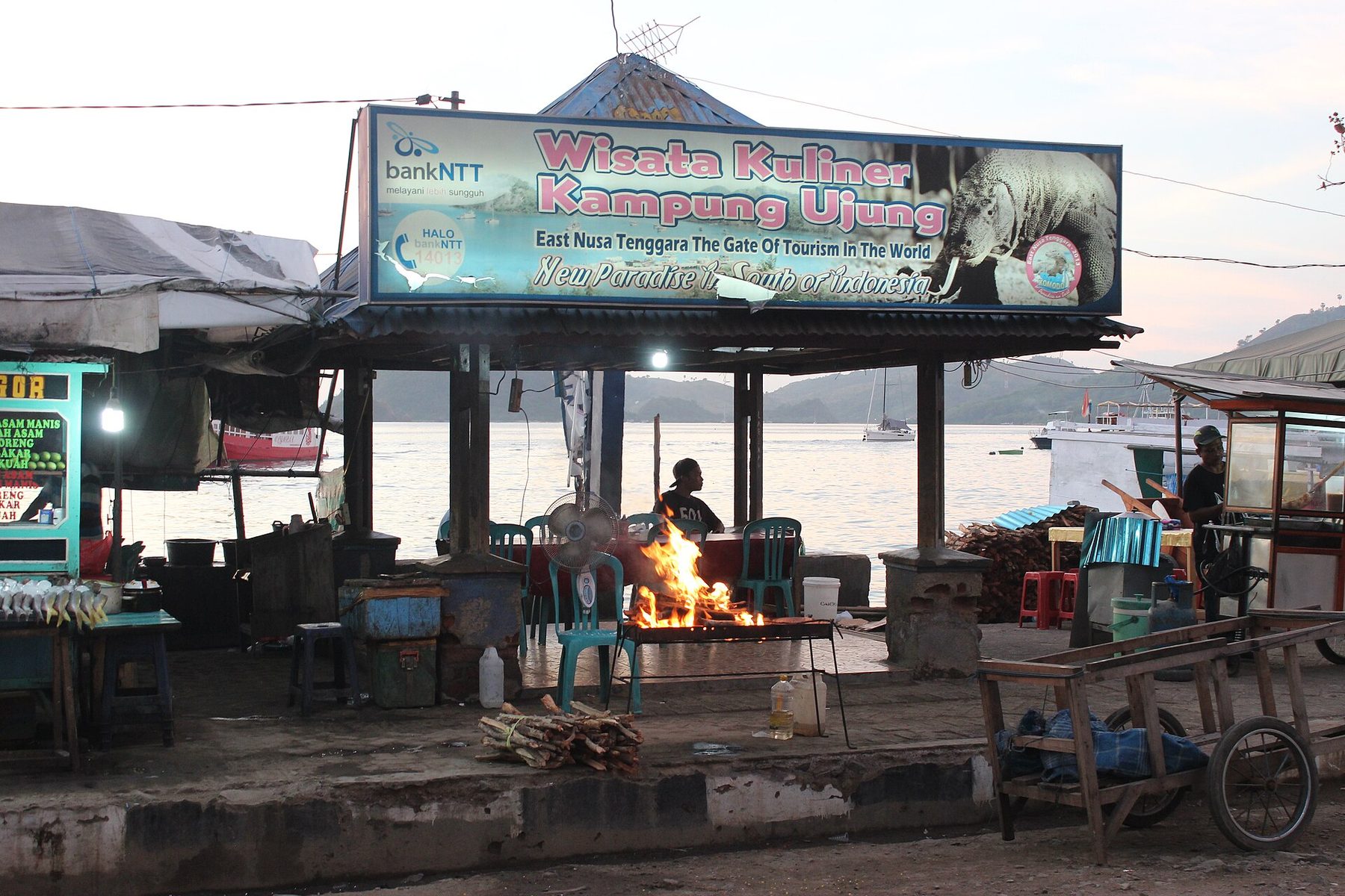 Street stalls in Labuan Bajo lit in the evening, with trestle tables, awnings and produce set out along the roadside