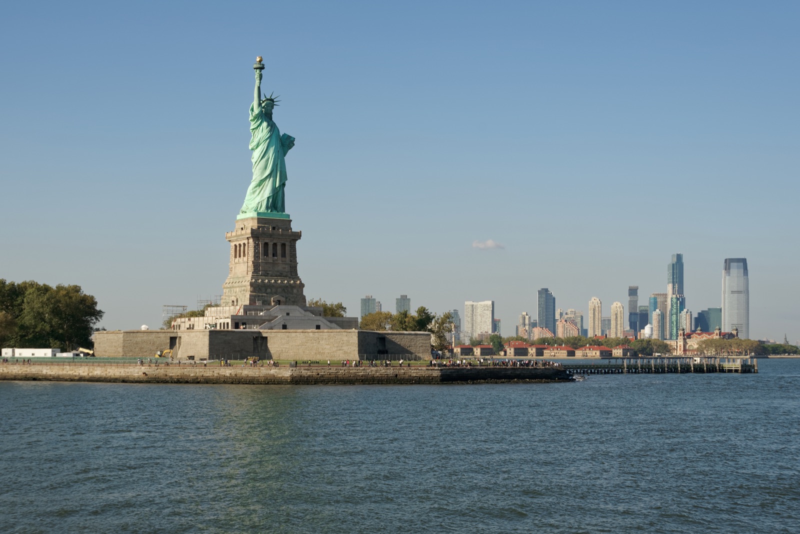 The Statue of Liberty on Liberty Island seen from the deck of the ferry, with Ellis Island and Jersey City to the right