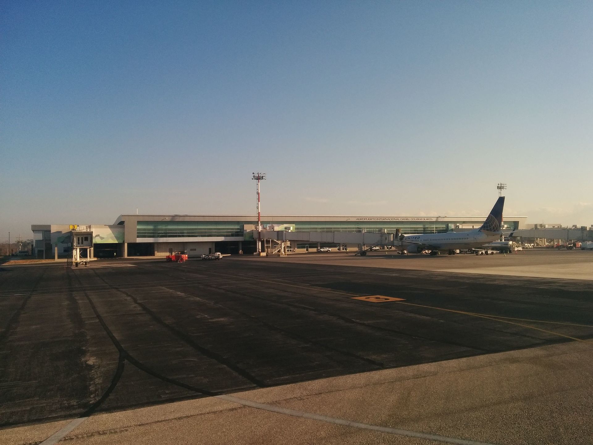The long single-story main building of Guanacaste Airport seen from the tarmac, with a covered walkway running along its front
