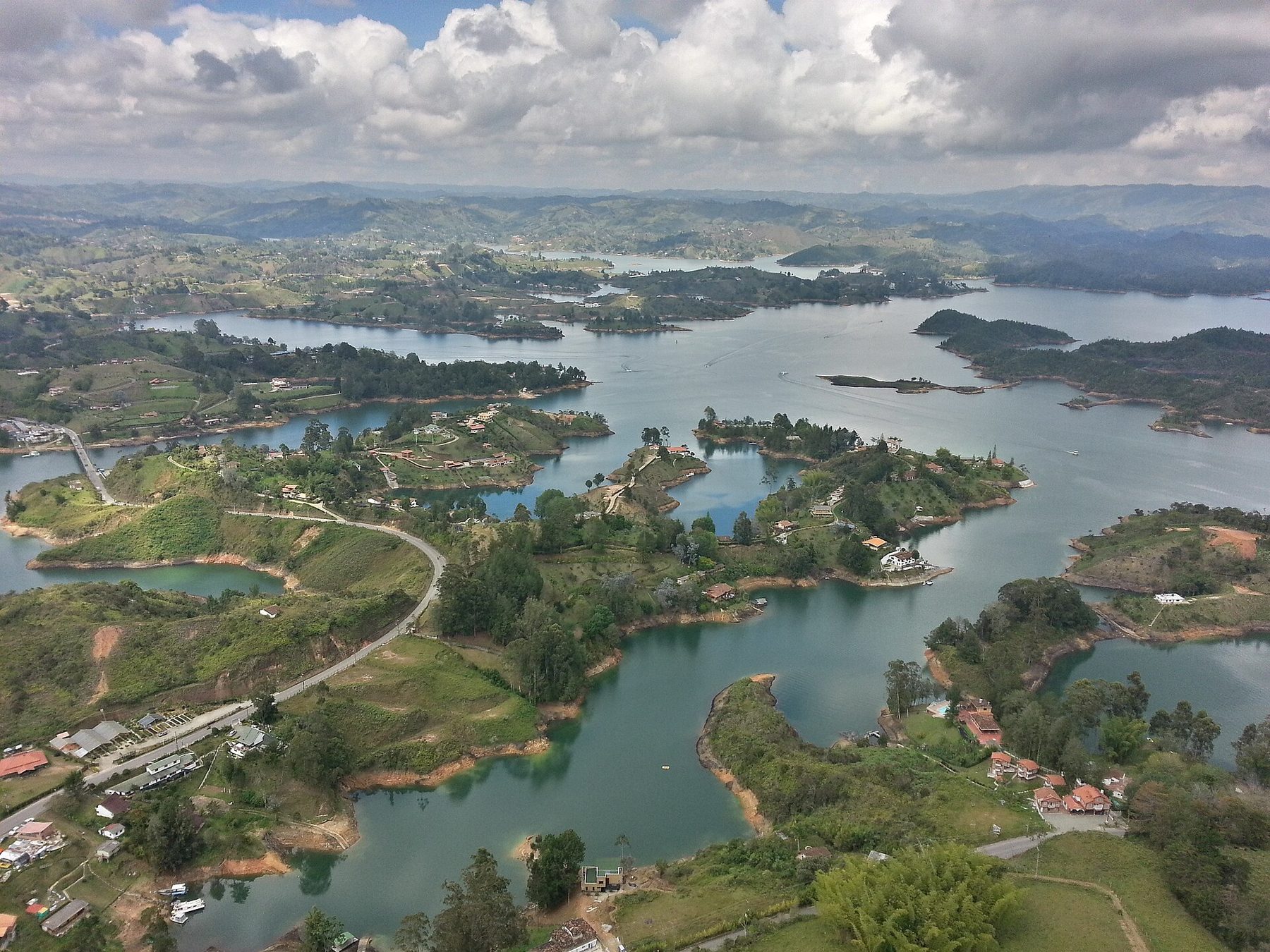 An aerial view over the green inlets and wooded islands of the Peñol-Guatapé reservoir in Antioquia, Colombia, with the town along the shore