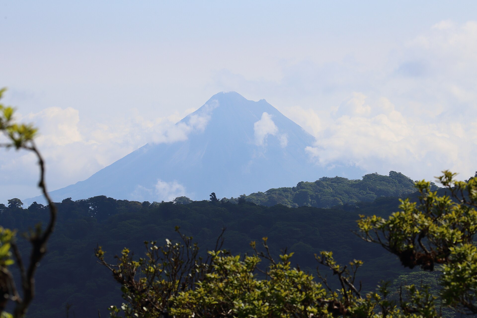 Arenal Volcano rising above dark forested ridges, seen from a sky tram cable car in Monteverde