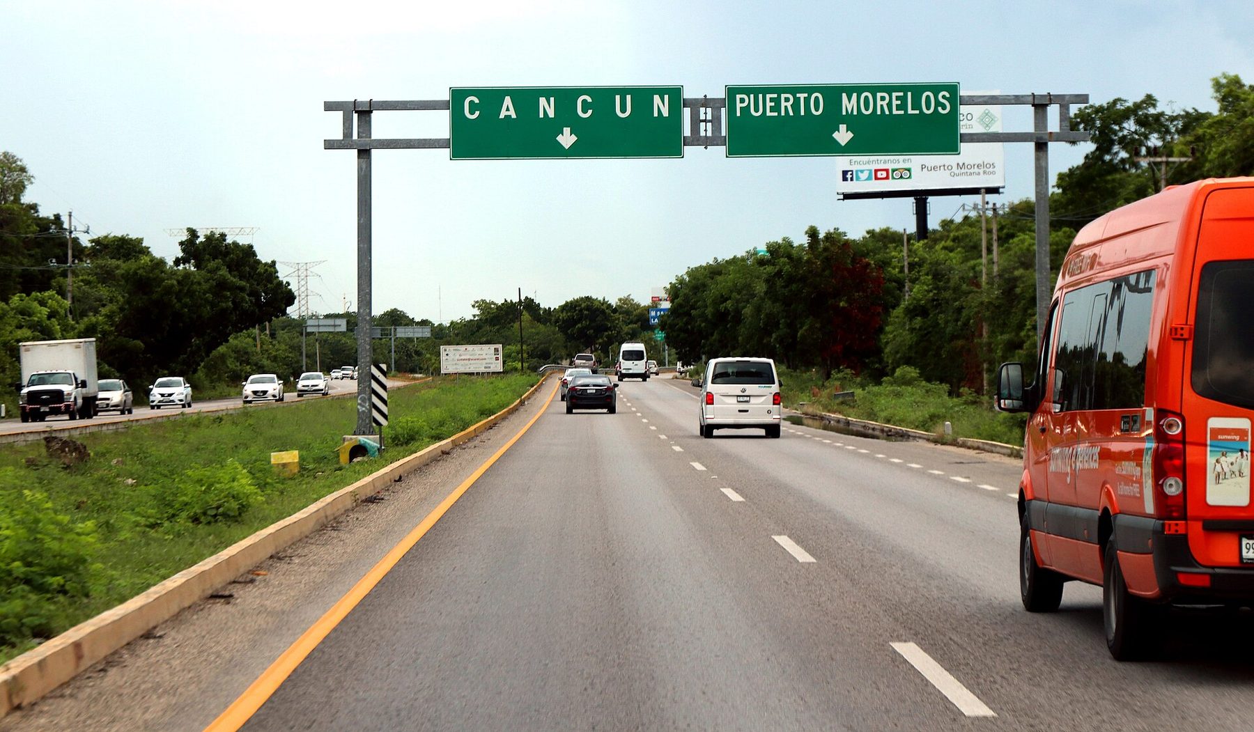 Traffic on Federal Highway 307 beneath a green overhead sign for Cancún and Puerto Morelos, Quintana Roo, Mexico