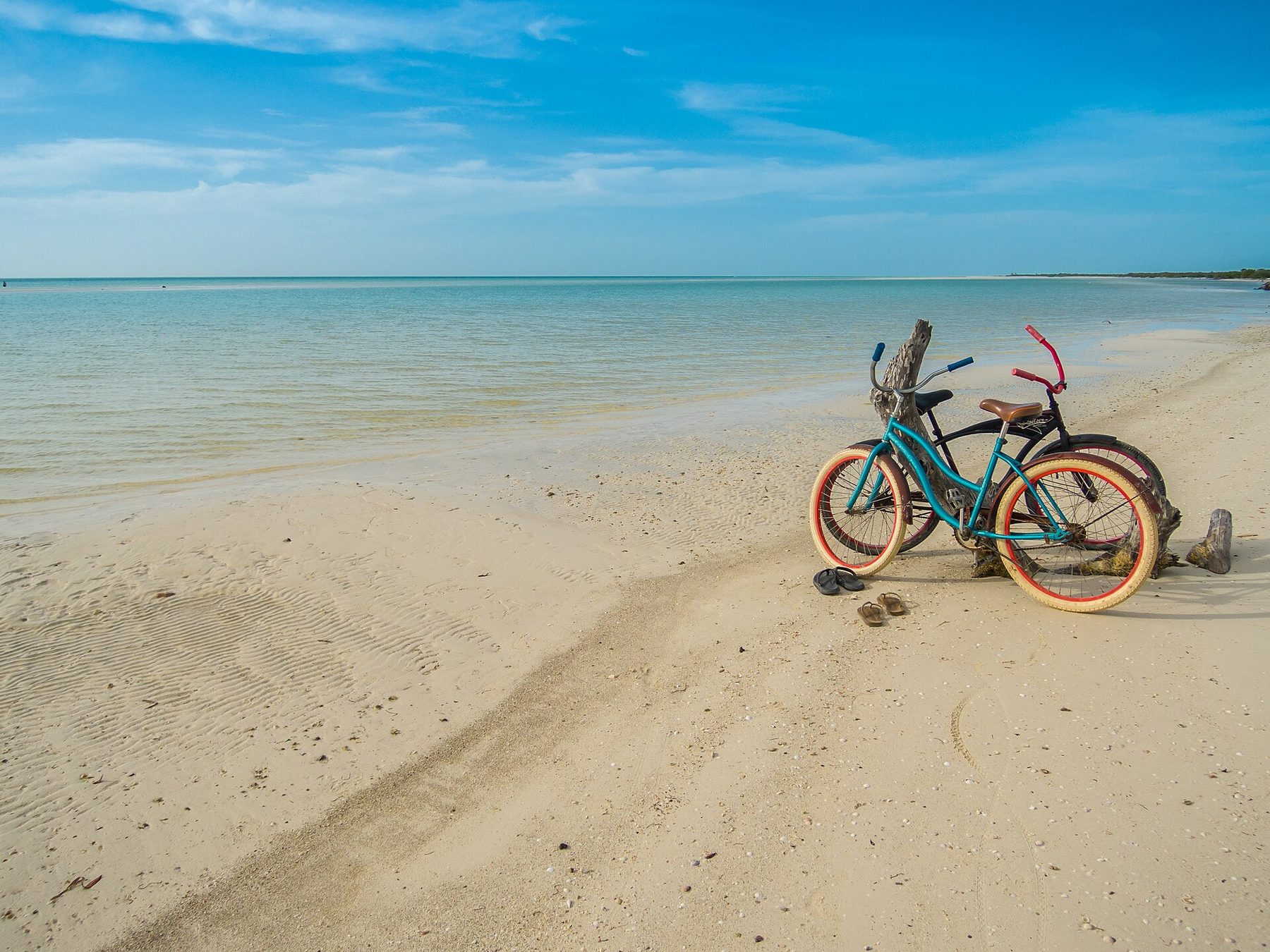 A wide empty stretch of pale sand and shallow water on Isla Holbox
