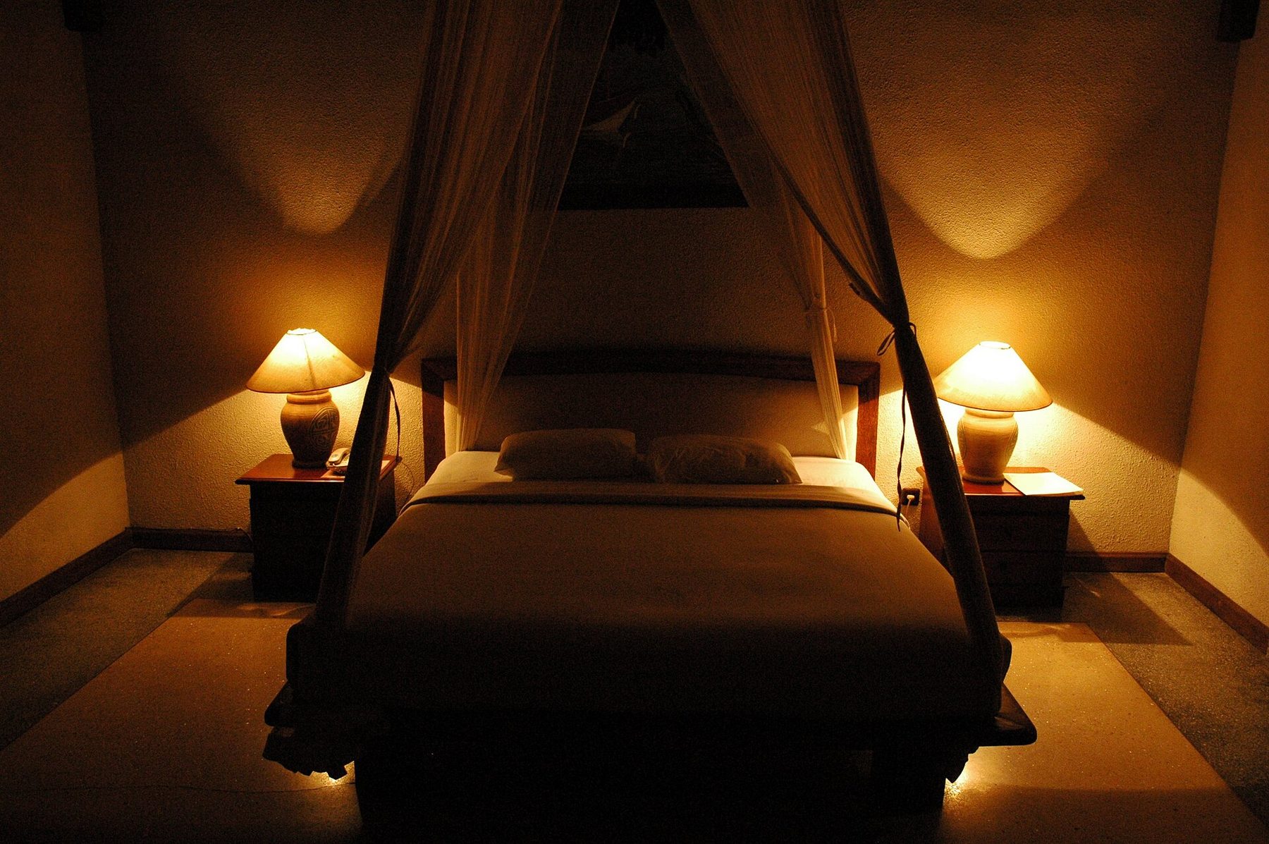 A bedroom in a rented Seminyak villa, with a low bed, white linen and dark timber ceiling beams