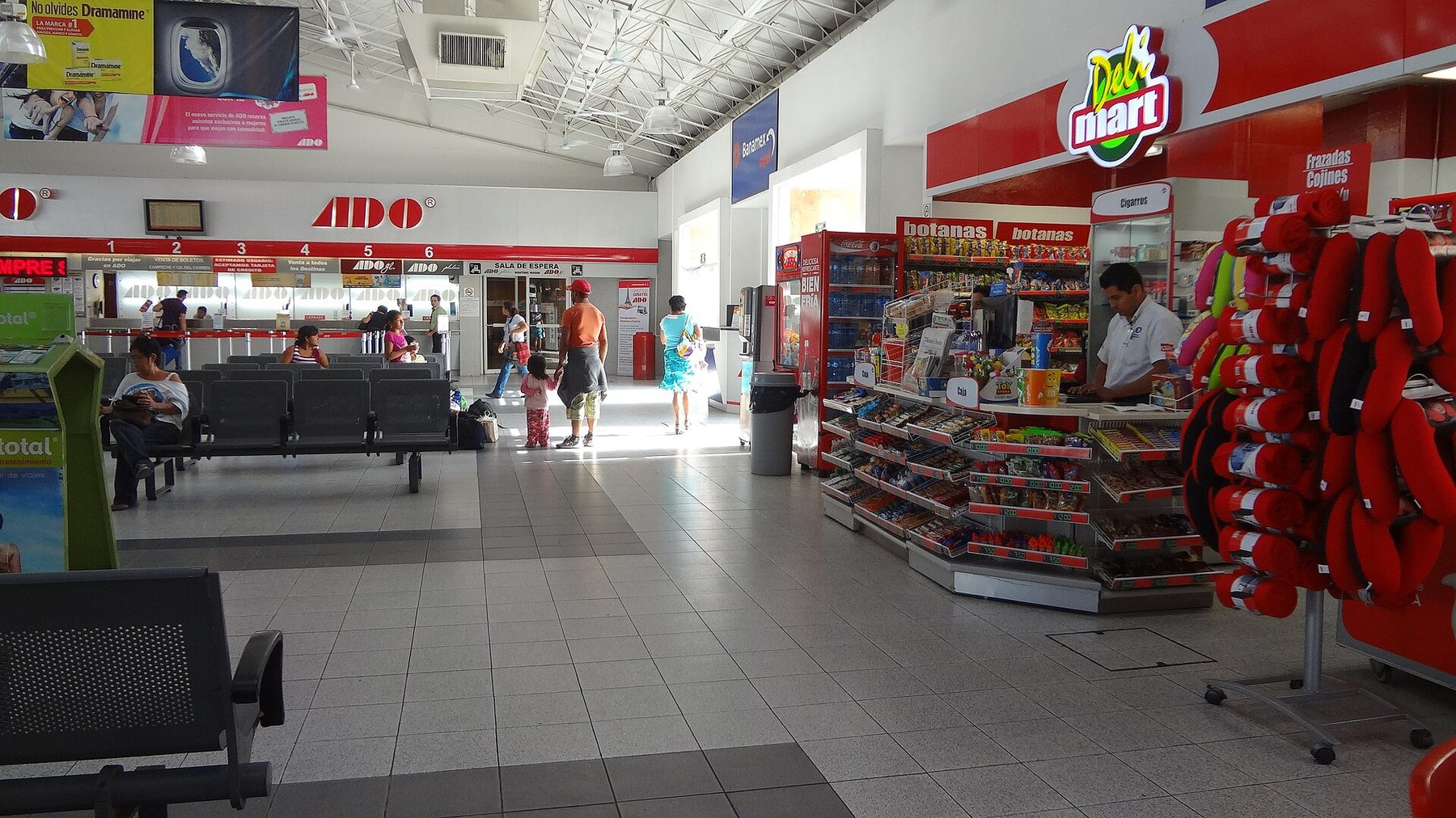 The entrance and platform of an ADO bus station in Mérida, with the ADO name on the building and coaches waiting under cover