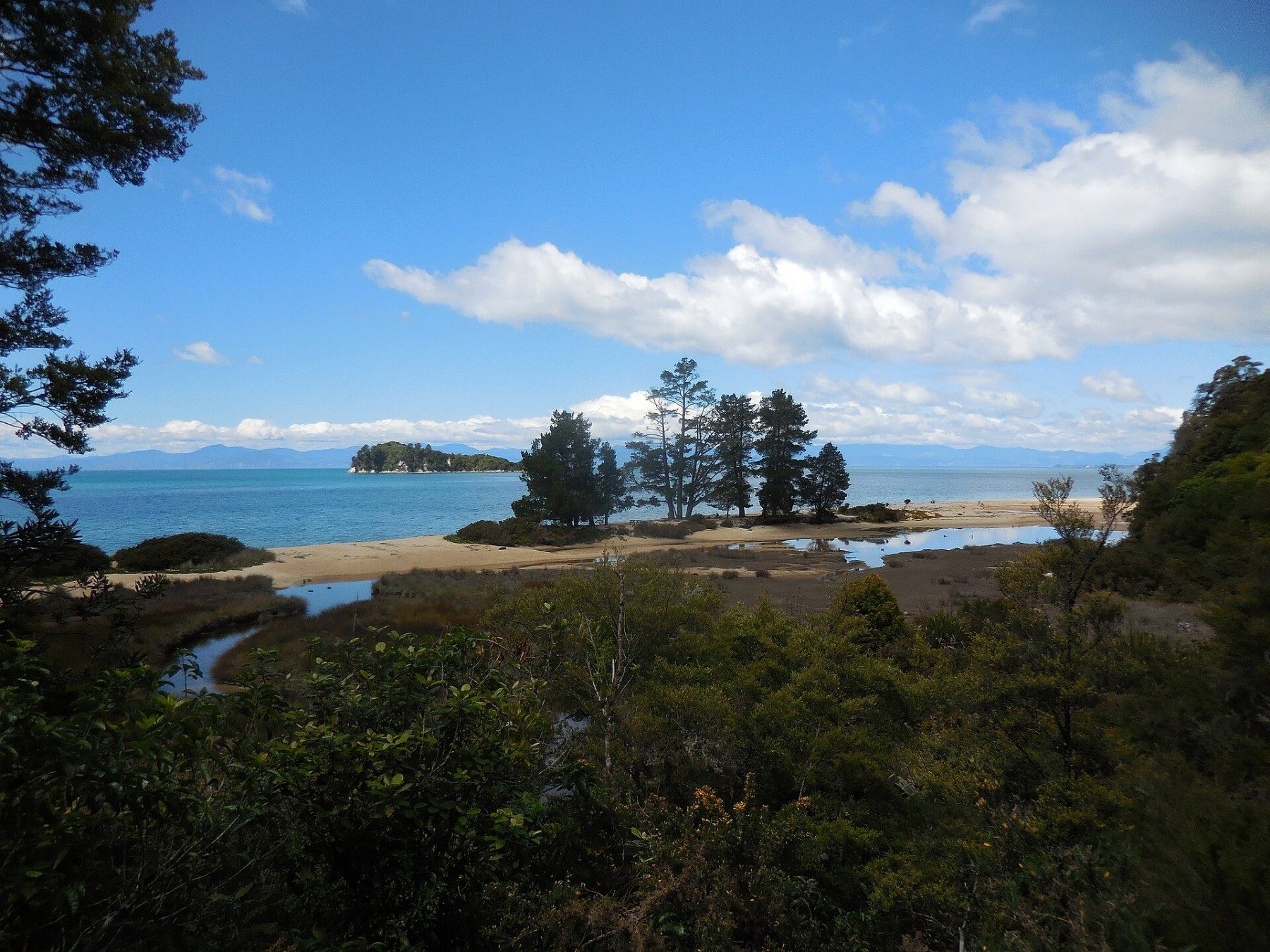 A coastal track above a sandy bay with an island offshore